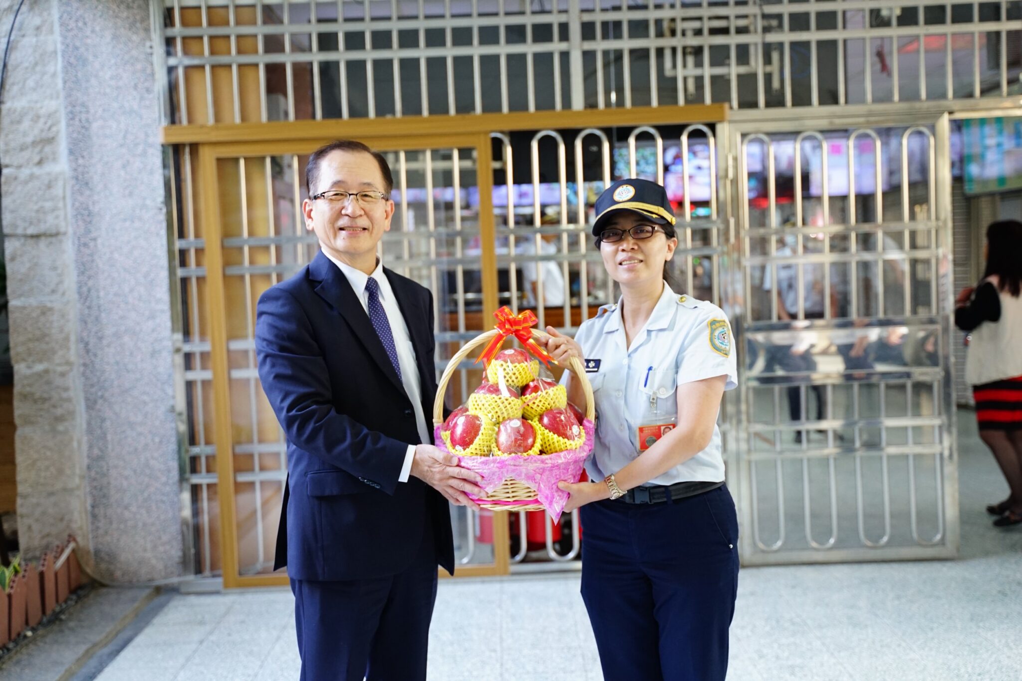 署長親自獻上蘋果籃，由第一線女管理員接受，意寓 祝福第一線同仁平平安安